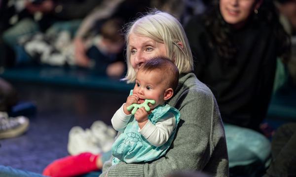An older lady sits with a baby on her lap.
