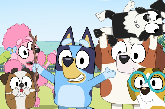 A group of animated cartoon dog characters from the children's TV show Bluey, gathered together in a park setting. In the centre is Bluey, a blue and tan heeler puppy with arms outstretched and a big smile. To the left is a pink poodle character holding a stick, standing behind a small brown and white bulldog puppy. To the right is a larger brown and white dog carrying a black and white puppy on its shoulders. In the front right is a small yellow and white dog wearing teal-framed glasses. The background shows green hills, trees, and a fence under a light blue sky.