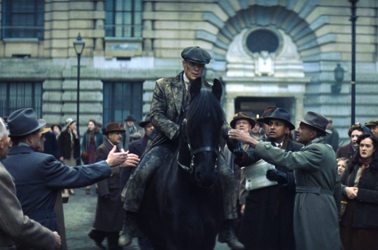 We see a man on horseback (Cillian Murphy) surrounded by a crowd in post-WWI Birmingham, with impressive period architecture in the background. The crowd reaches out to the man on horseback, whose clothes are muddy.