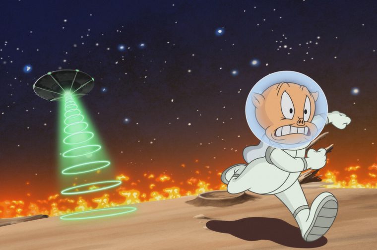Animated image of Porky Pig in a white spacesuit as he runs away from a flying saucer behind him, which is emanating a green ray. We see flames all around him as he runs across what appears to be the surface of a rocky planet.