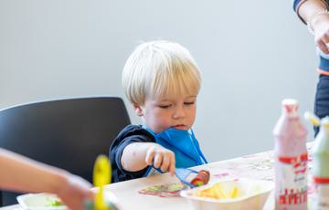 Young boy uses paint roller to make picture