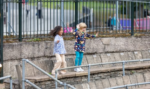 Two little girls dancing on the steps of an outdoor theatre, smiling