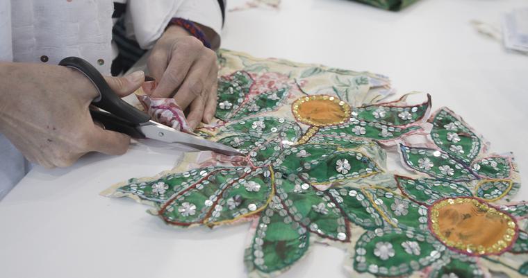 Woman's hands cutting material with sewing, embroidery and embellishments on fabric