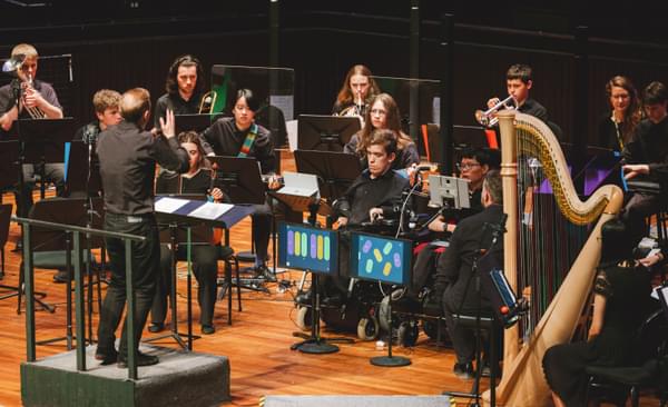 Group of disabled musicians playing classical concert led by a conductor