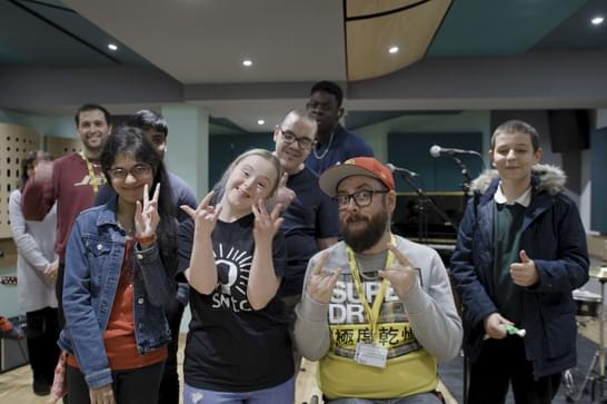 Inclusive music group pose for a photo, smiling children and teacher