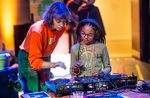 A woman and a young girl wearing headphones working with sound technology equipment