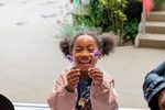 Little girl smiling holding up lavender flowers