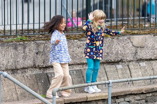 Two young girls smiling and dancing outside