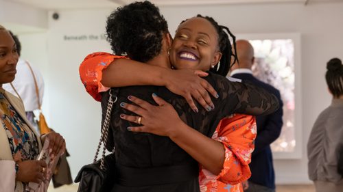 Two women hugging in an art gallery