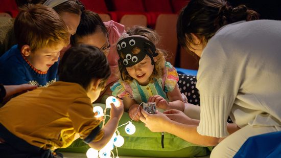 A group of smiling children play with round glowing lights