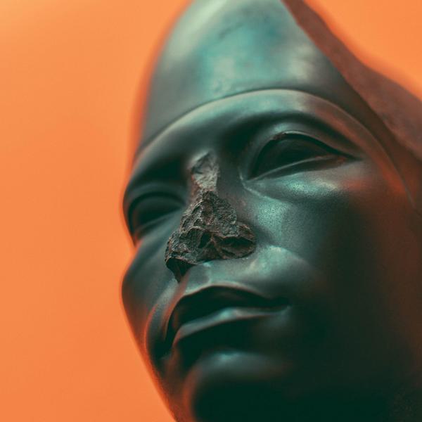 Close of a sculpture - figures face with bright orange background