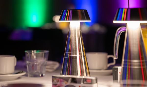 A close up of a table, with sliver mushroom lamps with rainbow colours lighting up the walls at the back