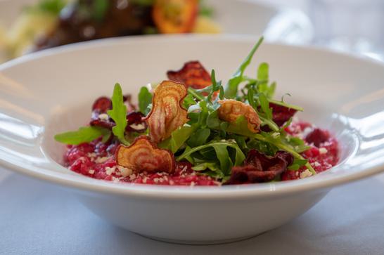 A dish of beetroot risotto is the main focus of this image, and it has been beautifully garnished with salad