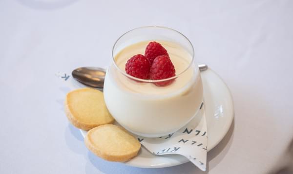 In the centre, a glass of Pana cotta topped with raspberries sits on a plate alongside some mini shortbread biscuits.