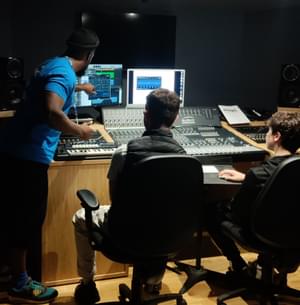 A music leader teaching young people how to use a mixing desk