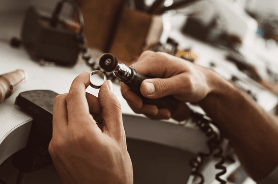 Someone is polishing a silver ring with a tool