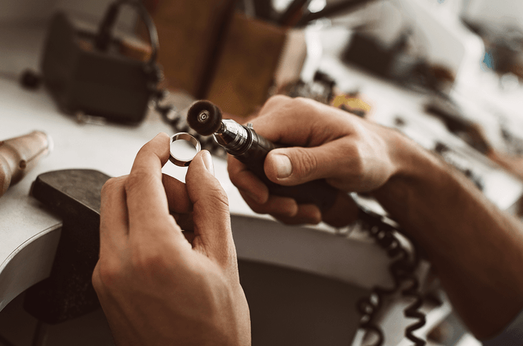 Someone is polishing a silver ring with a tool