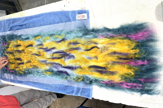 Colourful yellow, purple and blue felt is being laid on a table