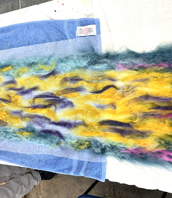 Colourful yellow, purple and blue felt is being laid on a table