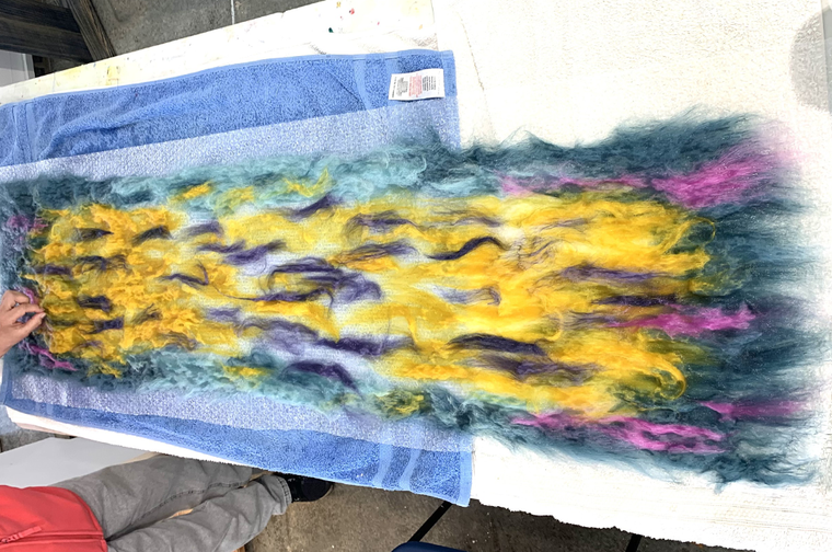 Colourful yellow, purple and blue felt is being laid on a table
