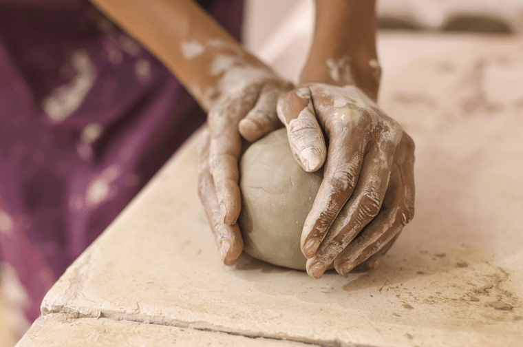 Someone is moulding a mound of clay with their hands