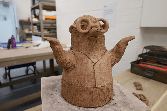 a mole wearing a waist jacket and glasses is made from clay, with his paws outstretched to the sides