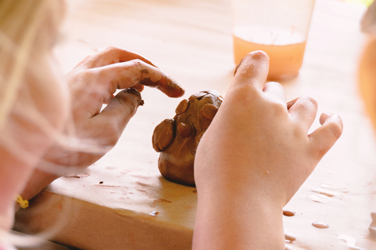A child is moulding a bird from clay