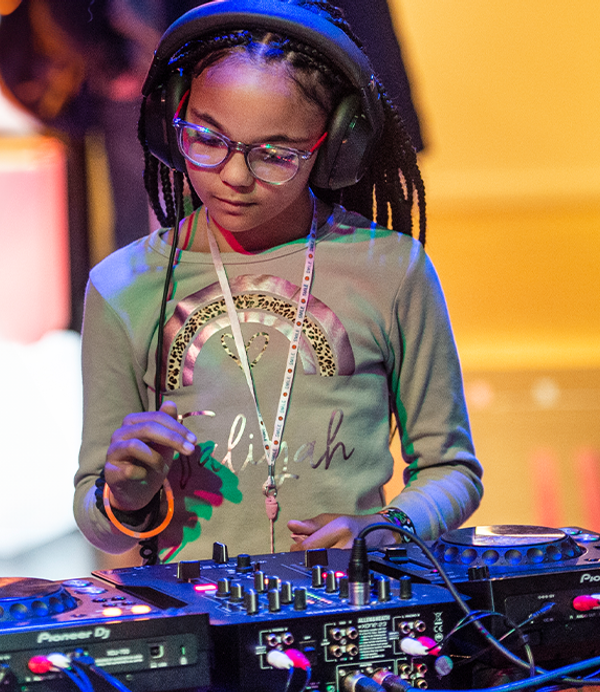 a young person is standing at some DJ Decks with headphones on