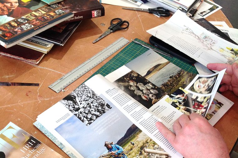 Someone is sat at a desk, flipping through magazines to find images