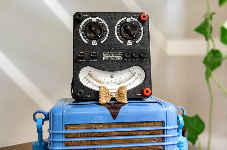 A blue and grey robots, with a head made from a radio and body from a speaker