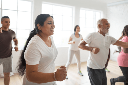 A group of older people are in a dance studio, appearing to be dancing