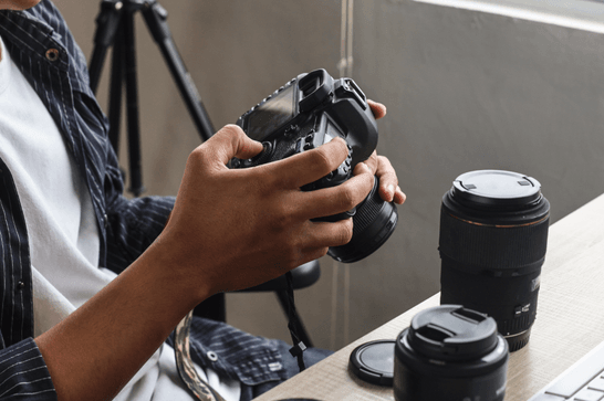 A person is sat at a desk, pressing the buttons of their camera