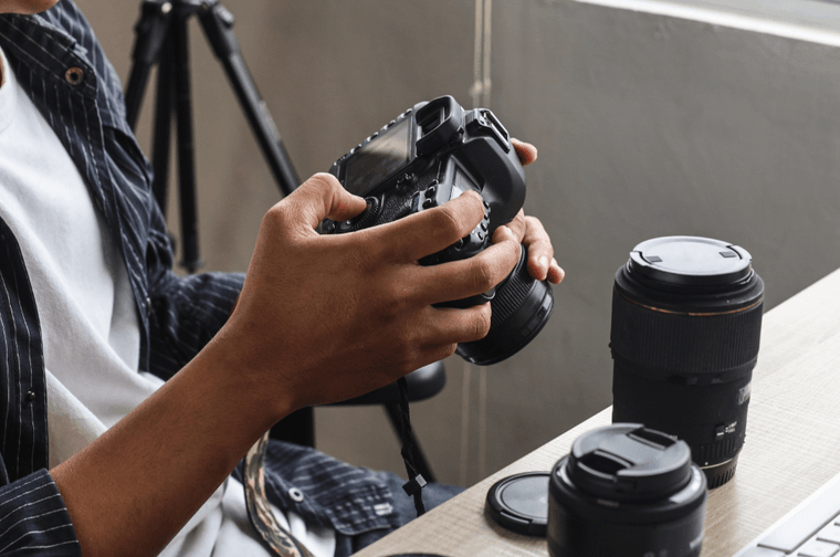 A person is sat at a desk, pressing the buttons of their camera