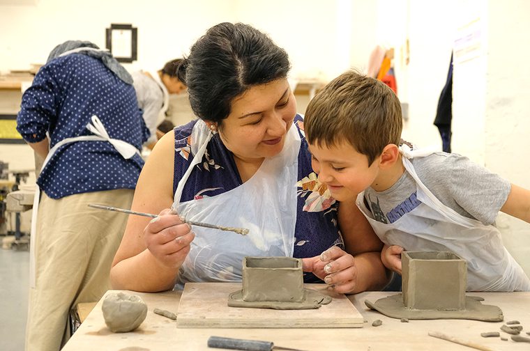 A mother and child are looking at a pot they're making together