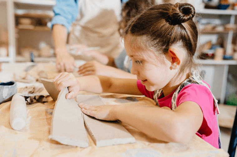 A child is moving strips of clay