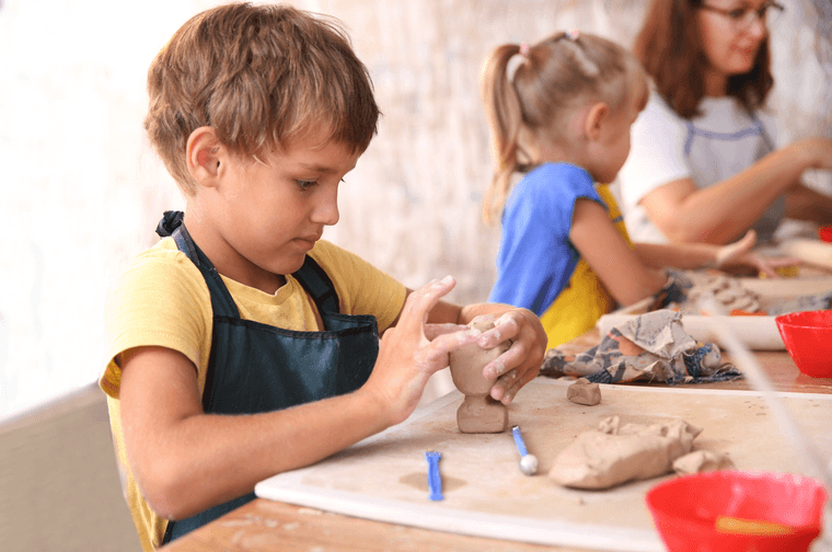 A child is moulding a lump of clay with their hands