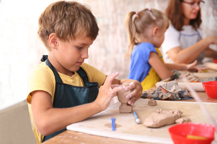 A child is moulding a lump of clay with their hands