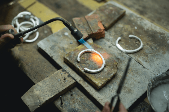A person is heating up a metal bracelet with a flame