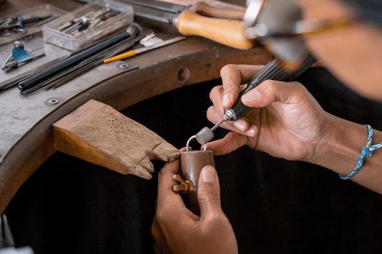 A person is polishing a silver ring at a jewellery work station