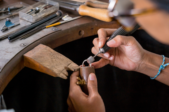 A person is polishing a silver ring at a jewellery work station