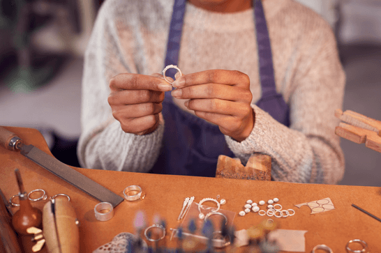 A person is sat at a workstation, holding a silver ring