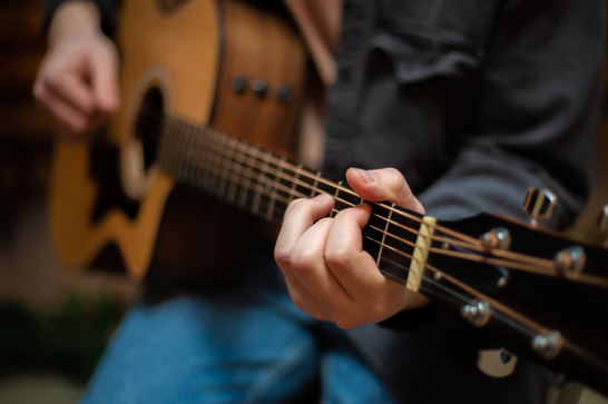 A person is holding a guitar, strumming it with a pic