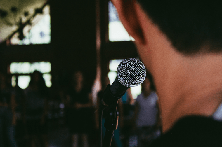 The back of someone's head, in the background a microphone is in focus