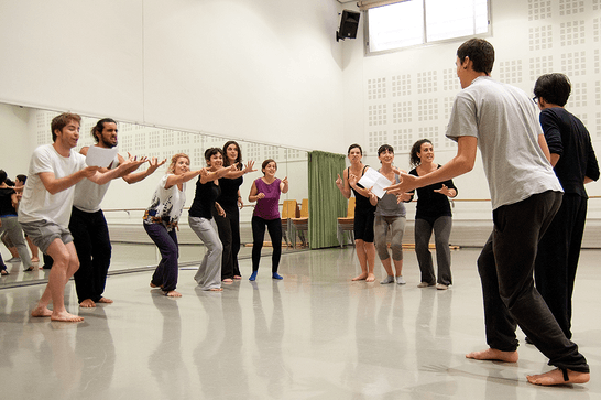 A group of people standing in a circle, making expressive hand and face gestures at each other