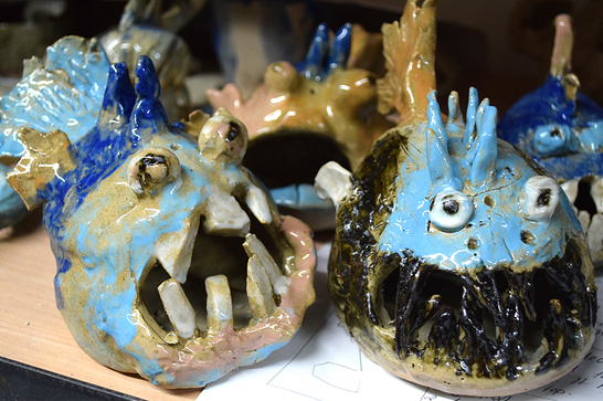 A collection of fish made from clay, with jagged teeth and bulging eyes