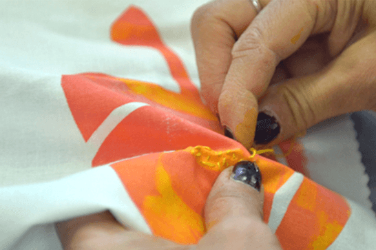 Someone is sewing a piece of colourful fabric