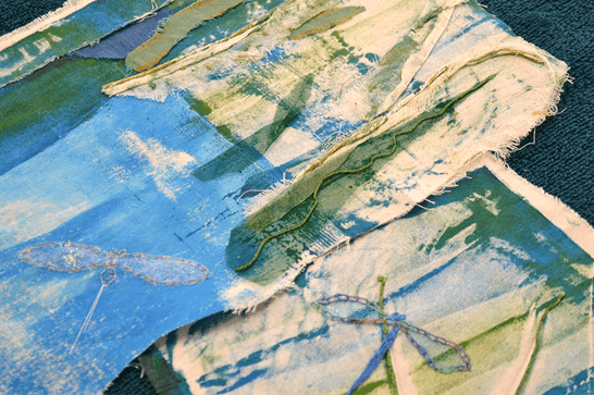 Blue and green dyed fabric have been patched together, with sewing on top of them