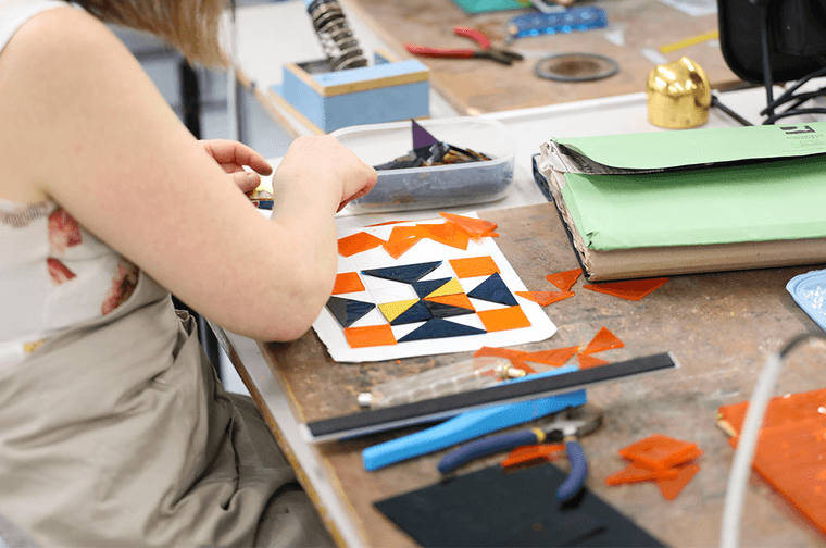 A person is arranging orange and black glass into a pattern