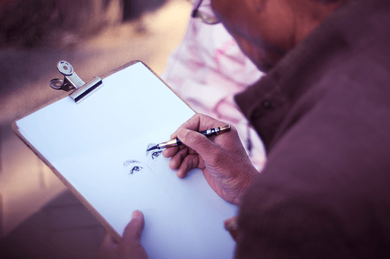 A person is drawing a face onto plain white paper