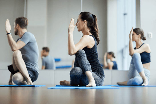 People sat on yoga mats, in a yoga pose